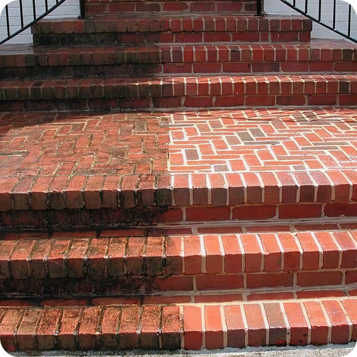 Side-by-side comparison of dirty and clean red brick steps after a pressure wash.