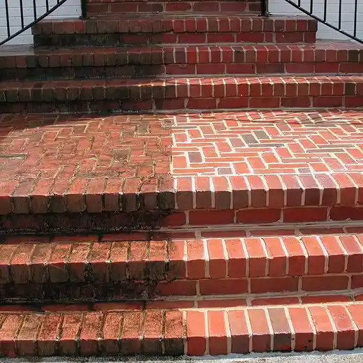 Side-by-side comparison of dirty and clean red brick steps after a pressure wash.