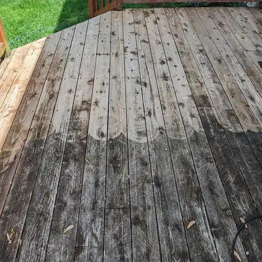 A wooden deck in the process of being cleaned, with a clear distinction between the dirty and cleaned wood planks.