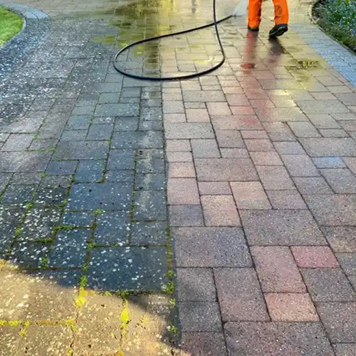 Before-and-after view of a stone paver walkway being pressure washed, showing the removal of moss and dirt.